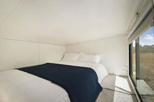 a white bed in a room with a window at Bellellen Park 2 by Tiny Away in Stawell