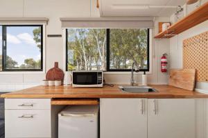 a kitchen with a counter with a microwave and two windows at Bellellen Park 2 by Tiny Away in Stawell