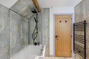 a bathroom with a tub and a shower with a wooden door at 2 Bed in Penmaenpool oc-m30050 in Arthog +24 photos