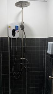 a shower in a bathroom with black tiles at Softbox Hostel in Ban Laem Thong Lang +15 photos
