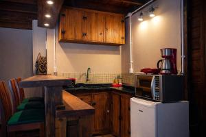 a kitchen with wooden cabinets and a microwave at Vilarejo Hospedagem in Ilha do Mel
