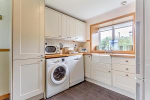 a kitchen with white cabinets and a washer and dryer at 3 Bed in Isle Of Skye oc-r31786 in Broadford