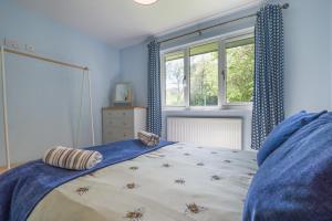 a bedroom with a bed with blue curtains and a window at 2 Bed in Bush oc-b31845 in Bude