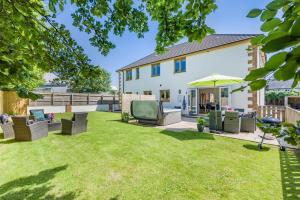 a garden with chairs and an umbrella at 5 Bed in Bradworthy oc-d31987 in Bradworthy