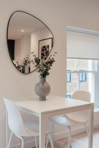 a white dining room table with a round mirror at Urban Rest Camden Town in London