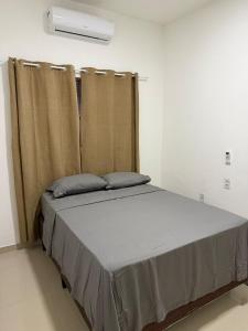 a bed in a room with a window with curtains at Pipa House Center in Pipa
