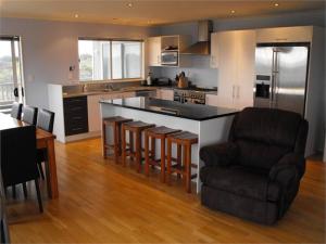 a kitchen with a bar with a couch and a chair at Hydrabad Views in Waitarere