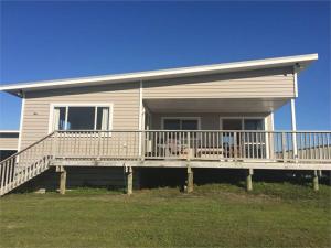 a house with a porch with two dogs sitting on it at Hydrabad Views in Waitarere