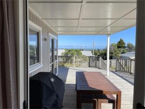 a porch with a table and a view of the ocean at Hydrabad Views in Waitarere