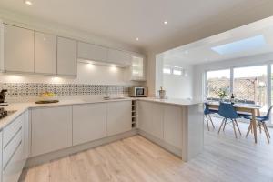 a kitchen with white cabinets and a table and chairs at 3 Bed in Greatstone oc-ek777 in Littlestone-on-Sea +20 photos