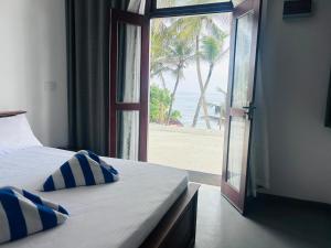 a bedroom with a door open to a beach at Surfing Tusker - Thalpe in Talpe