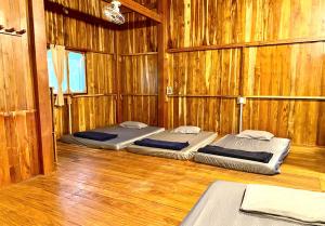 two beds in a room with wooden walls at Nui Tuong Village Stay in Tân Phú