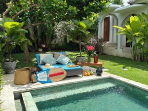 a garden with a couch and a swimming pool at Tropical Villa Canggu Beach in Dalung