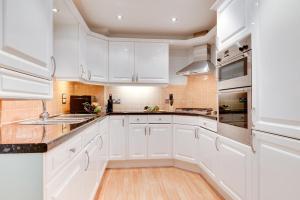 a white kitchen with wooden floors and white cabinets at 2 Bed in Carlyon Bay oc-crinni in Carlyon Bay
