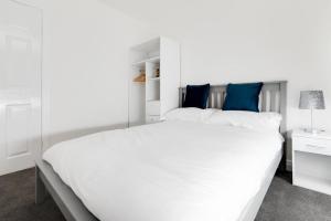 a white bedroom with a large white bed with blue pillows at 2 Bed in Seahouses oc-nb1974 in North Sunderland