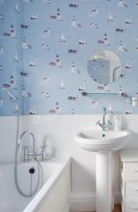 a bathroom with a sink and a shower curtain with boats on it at 5 Bed in Runswick oc-wa326 in Runswick +16 photos