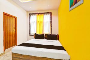 a bedroom with a large bed with a yellow wall at Hotel O Stayo in Patancheru
