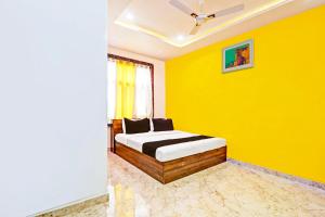 a yellow bedroom with a bed in a room at Hotel O Stayo in Patancheru