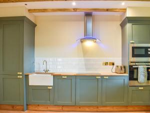 a kitchen with blue cabinets and a sink at Bumblebee Cottage-Uk39918 in Ballakinnag