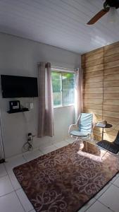 a living room with a chair and a large rug at Casa Rústica no centro de Araruama in Araruama