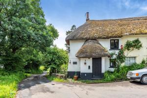 a thatched cottage with a car parked in the driveway at 2 Bed in Broadwoodkelly oc-j31818 in Broadwoodkelly