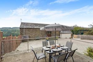 a table with chairs and an umbrella on a patio at 3 Bed in Woodford oc-w32062 in Kilkhampton