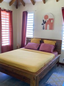 a bedroom with a large bed with yellow and purple pillows at Villa Surette in Capesterre
