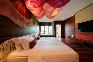 a bedroom with a large bed with a flat screen tv at Baan Krai Nao The Riverfront in Bangkok