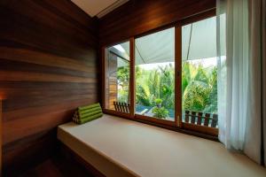 a window seat in a room with a view of the garden at Baan Krai Nao The Riverfront in Bangkok