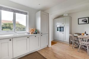 a kitchen with white cabinets and a dining table at 1 Bed in Seahouses oc-gd1735 in Seahouses