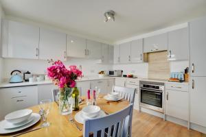 a kitchen with white cabinets and a wooden table with pink flowers at 2 Bed in Crackington Haven oc-p00596 in Crackington Haven