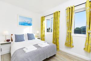a bedroom with yellow curtains and a bed with towels on it at 2 Bed in St. Ives oc-p00693 in Carbis Bay