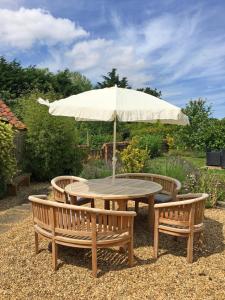 a wooden table with two benches and an umbrella at 3 Bed in Thursford oc-1793 in Thursford