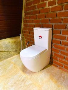 a white toilet sitting against a brick wall at The Classic Crown Sigiriya in Sigiriya +41 photos