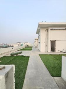 a white building with a grassy yard next to a building at Cozy corner in Gurgaon +2 photos