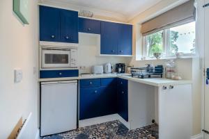 a kitchen with blue cabinets and a microwave at 1 Bed in North Walsham oc-f29380 in North Walsham +8 photos