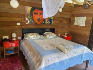a bedroom with a bed with a painting on the wall at Cabaña La Kirita EcoHotel in Bahía Solano
