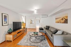 a living room with a couch and a tv at Apt 9 'Delphinius' @ Bay View Centro, Dunsborough in Dunsborough