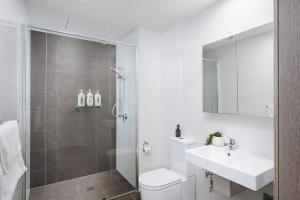 a bathroom with a toilet and a sink and a shower at 1010 - Elite Escape - Absolute Beachfront Luxury in Newcastle