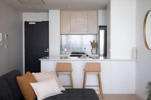 a living room with a couch and a kitchen at 1010 - Elite Escape - Absolute Beachfront Luxury in Newcastle