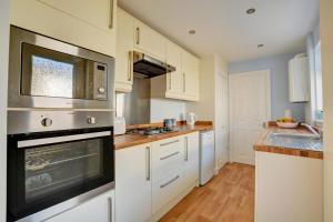 a kitchen with white cabinets and a microwave at 2 Bed in Hunstanton oc-1778 in Hunstanton +6 photos