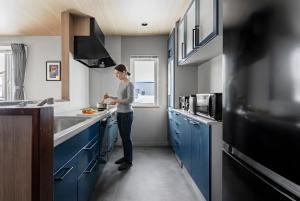a woman standing in a kitchen with blue cabinets at Astage Villa Kamifurano in Kami-furano