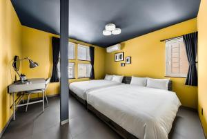 two beds in a room with yellow walls and a desk at Astage Villa Kamifurano in Kami-furano