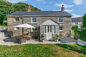 a stone house with a table and an umbrella at 2 Bed in Breage oc-jobcot in Breage