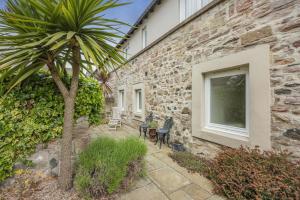a stone house with a palm tree next to a building at 3 Bed in Bamburgh oc-gd0468 in Bamburgh