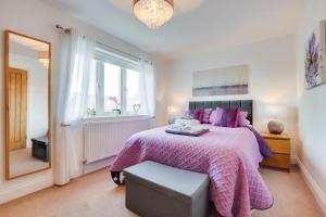 a bedroom with a bed with a purple blanket and a mirror at 4 Bed in North Sunderland oc-gd1890 in North Sunderland