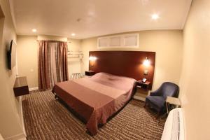 a hotel room with a bed and a chair at Santa Cruz Inn in Riverside