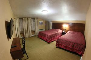 a hotel room with two beds and a table at Santa Cruz Inn in Riverside