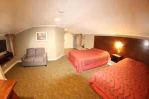 a hotel room with two beds and a chair at Santa Cruz Inn in Riverside