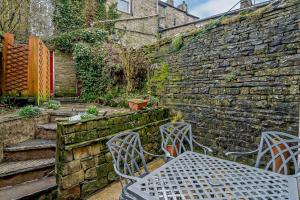 a table and chairs in a garden with a stone wall at 3 Bed in Hawes oc-hhmy23 in Hawes